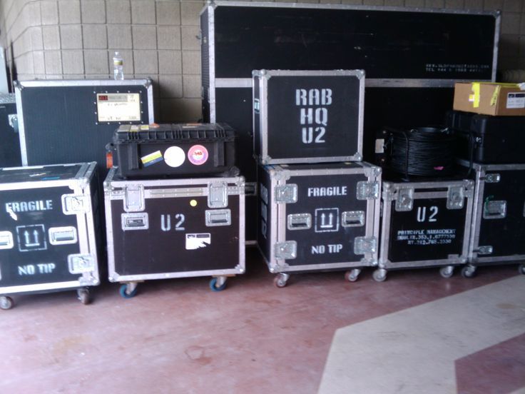 Schwarze Flightcases mit U2-Beschriftung in einem Logistiksystem für Tourneen.